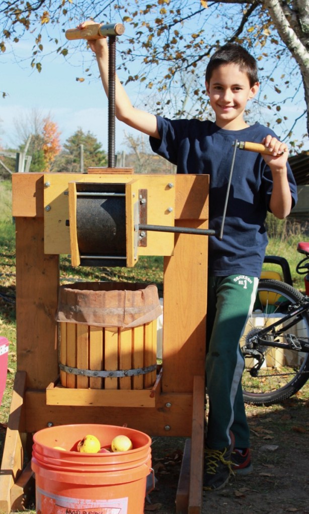 Keiran Roopchand turning the cider press at Pumpkin Vine Family Farm in Somerville.