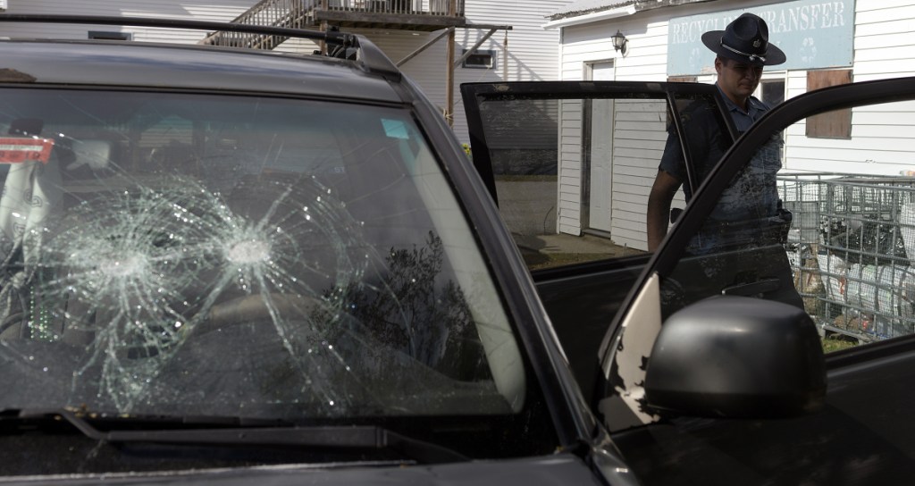 State Trooper Jim Moore examines an SUV that had its windshield smashed in the parking lot of the Litchfield Country Store Wednesday. Troopers are working with the Office of State Fire Marshal to determine the origin of a fire that was ignited in the car. Firefighters from Litchfield were called to the scene. No injuries were reported, according to police.
