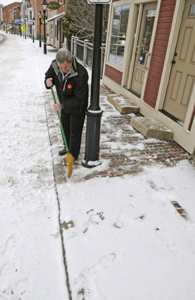 Jack Turner sweeps snow from the sidewalk in front of his jewelry shop on March 7, 2017, in downtown Hallowell.