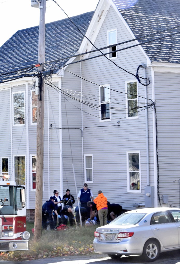 Rescue and ambulance personnel administer aid to a man who reportedly fell Tuesday from the open third-floor window, above, at the Home Place Inn, an apartment complex on College Avenue in Waterville.