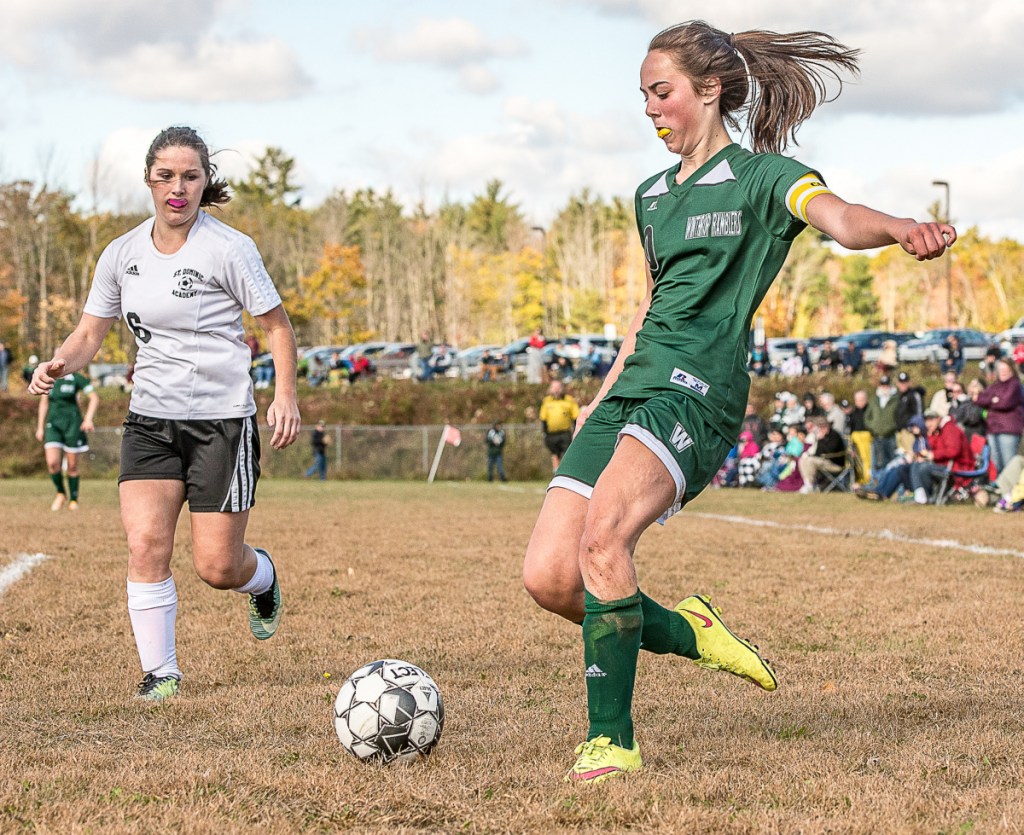 Winthrop's Kena Souza kicks the ball as St. Dominic's Emma Wolverton comes into the play from the left during Saturday's Class C South preliminary game in Winthrop.