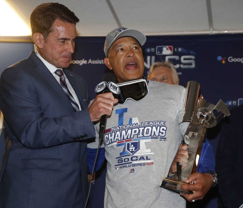 Los Angeles Dodgers' manager Dave Roberts holds the championship trophy after beating the Milwaukee Brewers in Game 7 of the National League Championship Series on Saturday in Milwaukee. The Dodgers won 5-1 to advance to the World Series.