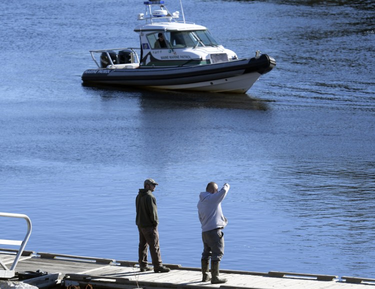 Friends and relatives watch Friday as the Marine Patrol searches the Kennebec River in Richmond for Mark Johnston, 64. Authorities were searching by air, on the water and diving after Johnston disappeared Thursday night. They found a body Friday, but the person's identity was not confirmed immediately.
