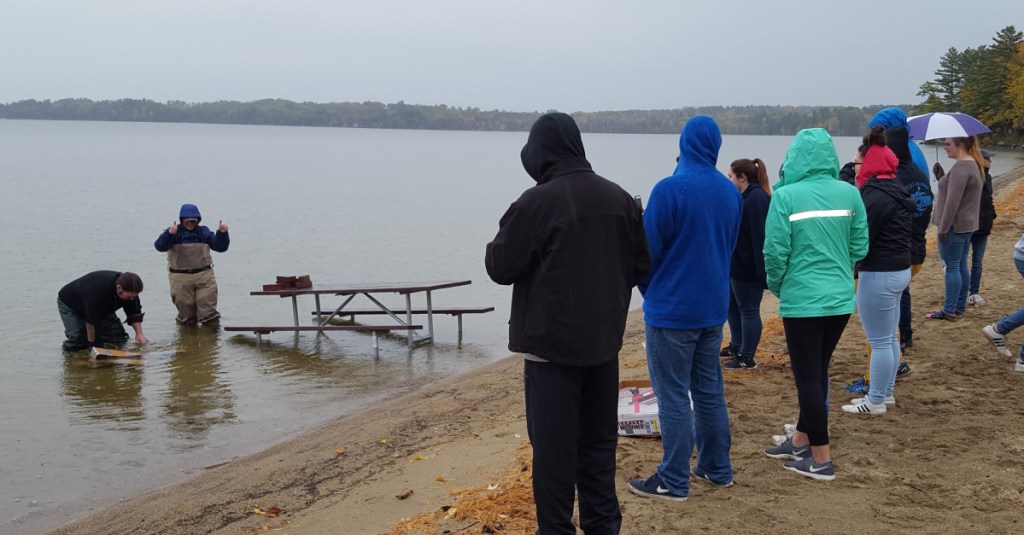 Students from central Maine watch as judges Michael Chamberland, left, and Ellen Benson test the seaworthiness of their homemade boats at JMG's Leadership Education Conference in Rome, Maine.