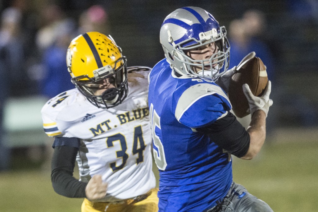 Lawrence fullback Alex Higgins hauls in a pass as Mt. Blue  Zack Delano gives chase during a Pine Tree Conference Class B quarterfinal round game Friday night at Keyes Field in Fairfield.