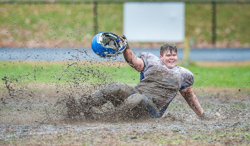 Oak Hill's James Borkowski slides through the mud after the Raiders defeated rival Lisbon in overtime in the Class C South quarterfinals Saturday in Lisbon.