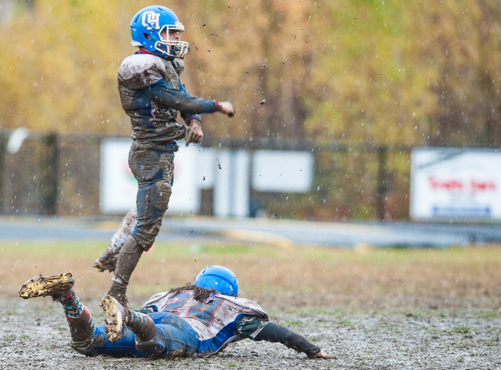 Oak Hill's Caleb Treadwell, top, celebrates after diving through the mud as teammate Gabriel Bergeron, bottom, takes his turn after the No. 7 Raiders defeated No. 2 Lisbon in overtime in the Class C South quarterfinals Saturday in Lisbon.