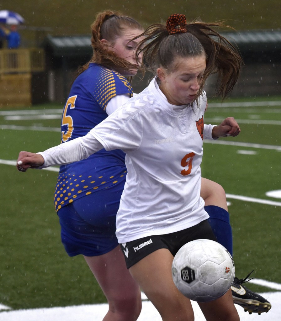 Winslow's Alison Stabins, front, reaches tries to fend off  Hermon's Emily Smith during a Class B North semifinal against Hermon on Monday at Hampden Academy.