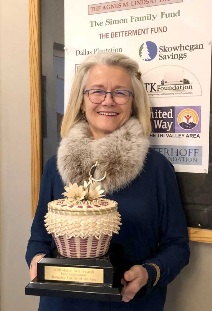 Val Zapolsky, President of the Rangeley Friends of the Arts, displays the hand-crafted ash basket received as the award for being named the Rural Arts Organization of 2018 by the Maine Arts Commission.
