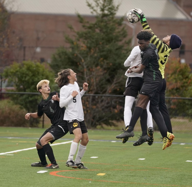 Maranacook keeper Ryan Worster grabs the ball before Diraige Dahia of Waynflete can get his head on it during the Class C South regional final Wednesday in Portland. At left is Oliver Burdick of Waynflete and Carter McPhedran of Maranacook.