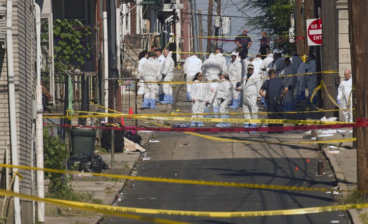 Federal and local authorities investigate along North Hall Street in Allentown, Pa., on Sunday after a fiery car explosion rocked the neighborhood, killing three males on Saturday night.