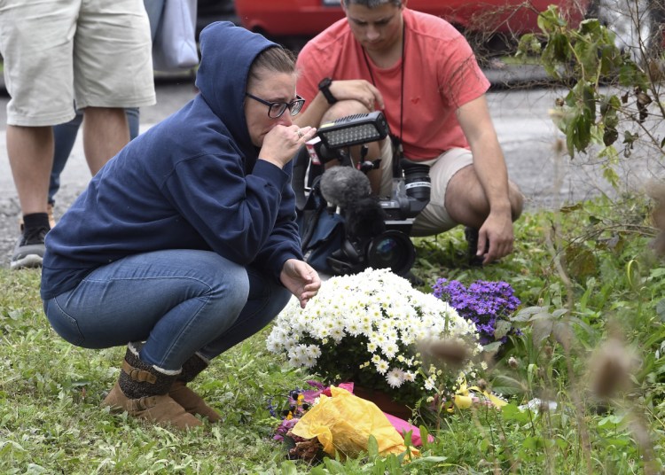 A woman kneels after placing flowers on Sunday at the scene where 20 people died when a limousine crashed into a parked SUV a day earlier in Schoharie, N.Y.