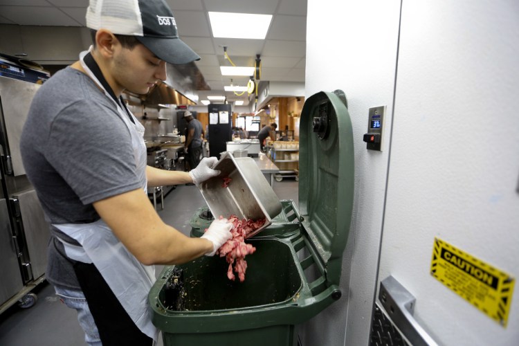 Konrad Navarrete, part of the kitchen crew at Dos Toros restaurant in New York, dumps meat scraps into the organics processing bin. New York City has begun requiring chain restaurants to separate their food waste from other trash.