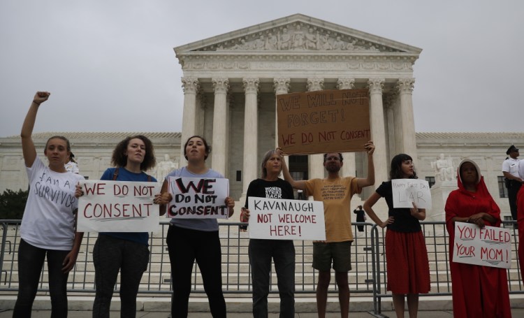 A small number of activists protest in front of the Supreme Court on Tuesday while Brett Kavanaugh is welcomed by his new colleagues. The court heard arguments over increased prison sentences for repeat offenders.