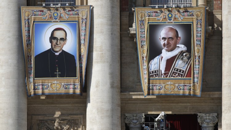 The tapestries of Roman Catholic Archbishop Oscar Romero, left, and Pope Paul VI hang from a balcony of the facade of St. Peter's Basilica at the Vatican. Pope Francis will elevate them to sainthood Sunday.