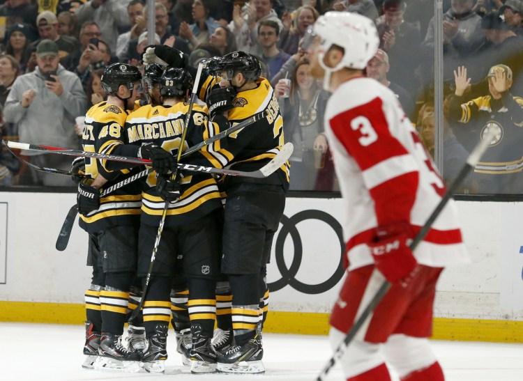 Bruins players surround David Pastrnak after one of his two second-period goals on Saturday as Red Wings defenseman Nick Jensen looks up at the replay. Boston won 8-2 at home.