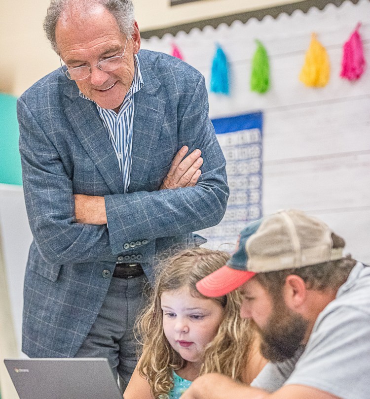 David Roux peeks over the shoulders of Audrey and Scott Scanlon, who are busy coding for Minecraft during Wednesday's Learn-to-Code night at Montello Elementary School in Lewiston.
