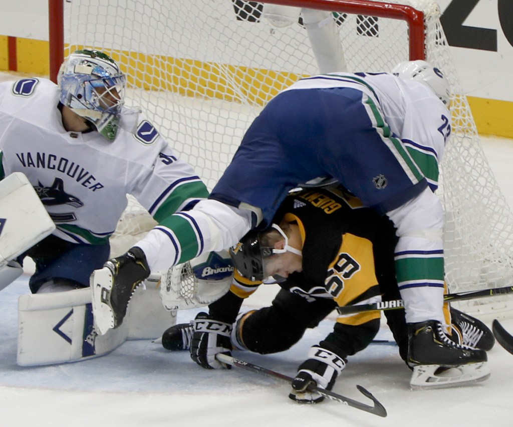 Canucks defenseman Alexander Edler, top right, tumbles over the Penguins' Jake Guentzel beside goaltender Anders Nilsson during the first period of Vancouver's 3-2 overtime win on Tuesday.