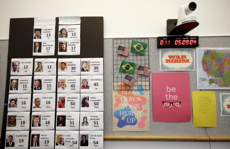 Photos of Brazilian election candidates and a clock counting down the election in Brazil are shown on a wall in the war room, where Facebook monitors election related content on the platform, in Menlo Park, Calif., Wednesday, Oct. 17, 2018.