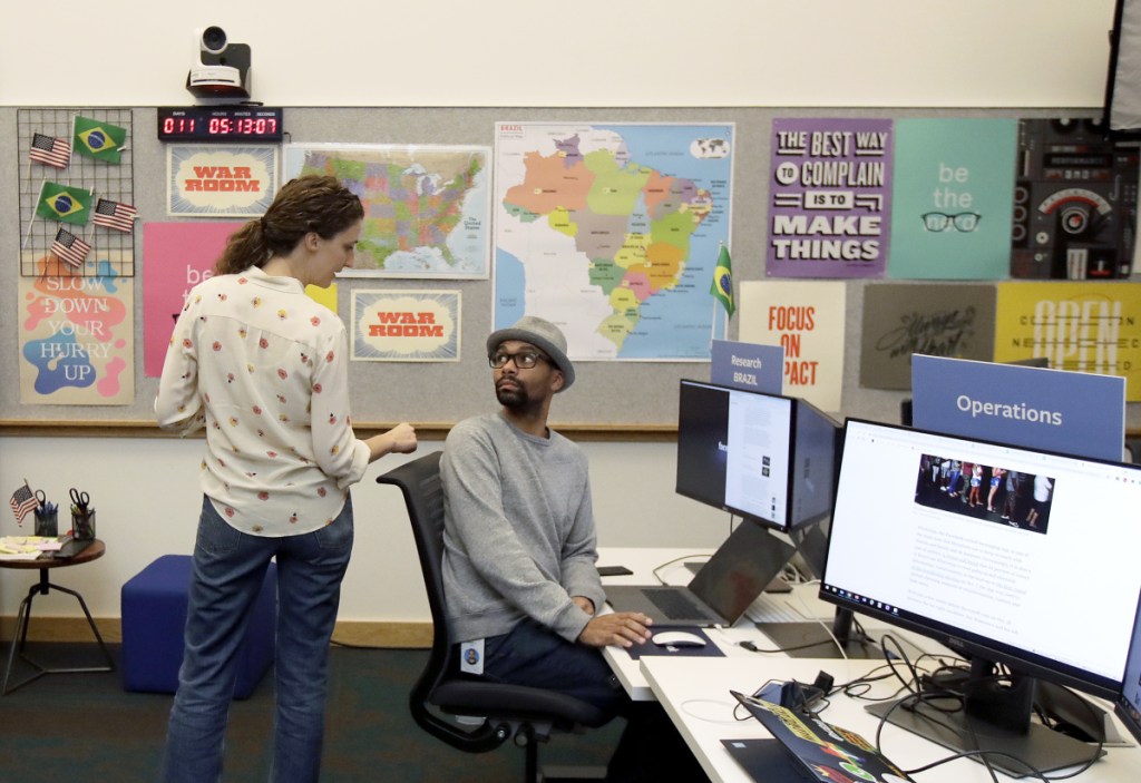 Lexi Sturdy, election war room lead, left, talks with researcher Andre Souza during a demonstration in the war room, where Facebook monitors election related content on the platform, in Menlo Park, Calif., Wednesday, Oct. 17, 2018.