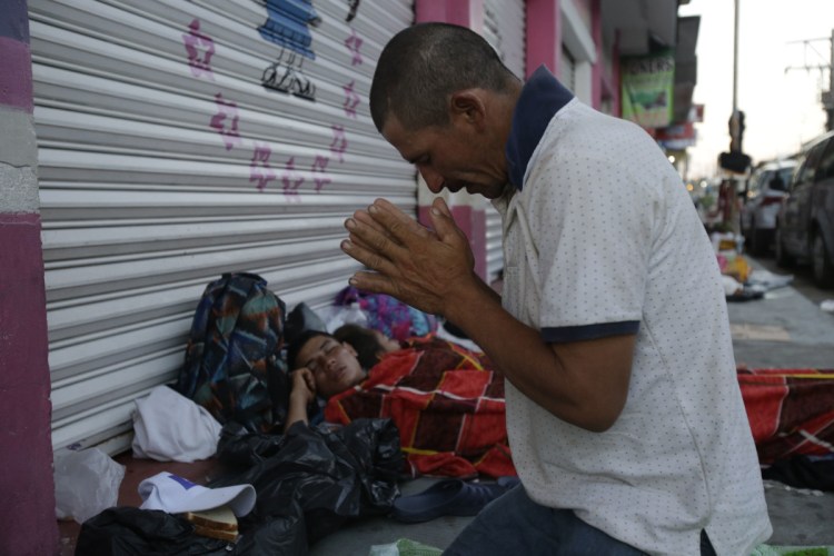 Marvin Sanabria, a Central American migrant traveling with a caravan to the United States, kneels in prayer after waking up in Huixtla, Mexico, on Tuesday. The caravan, estimated to include more than 7,000 people, had advanced but still faced more than 1,000 miles, and likely much farther, to the end of the journey.