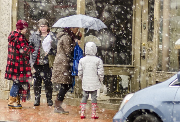 People walk through a flurry of wet snow Saturday on Water Street in Hallowell. It was the start of a nor'easter that blew through over the weekend.