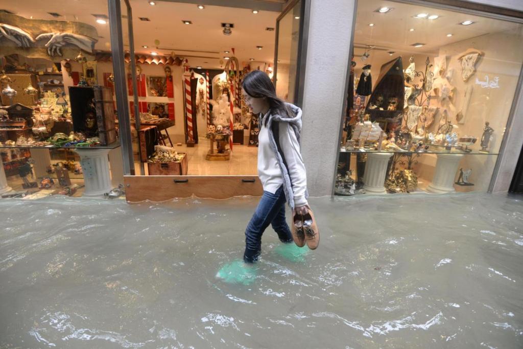 A woman walks in a flooded street of Venice, Italy, on Monday, as 70 percent of the lagoon city was flooded by waters rising more than five feet above sea level, according to city officials.