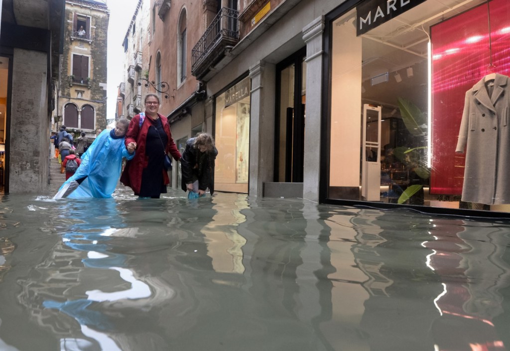 People walk in a flooded street of Venice, Italy, on Monday, as 70 percent of the lagoon city was flooded by waters rising more than five feet above sea level, according to city officials.