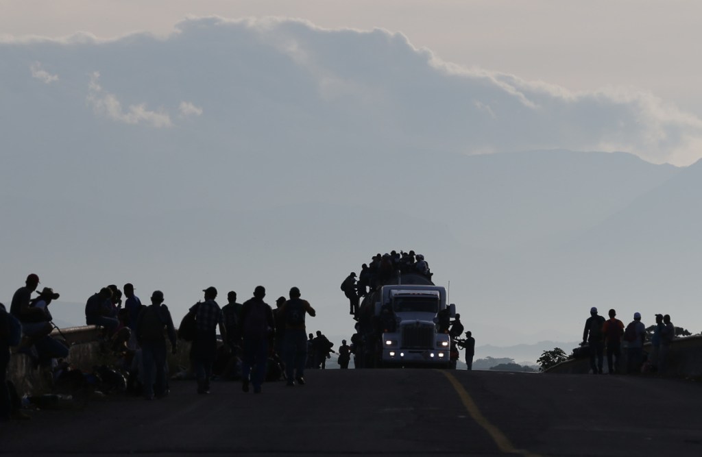 Migrants crowd atop a tanker truck while others walk or wait for rides in Niltepec, Mexico, on Tuesday.