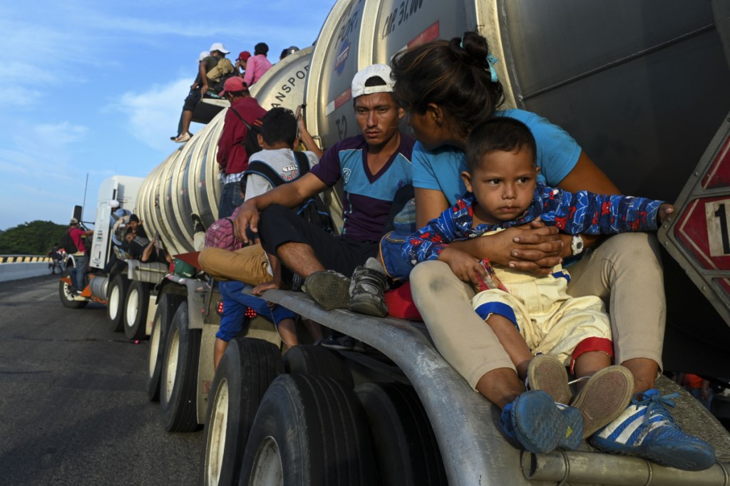 Some of the thousands of migrants traveling in a caravan toward the U.S. border, including Miguel de Jesus, 4, catch a ride atop a truck on a highway in Santiago Niltepic, Mexico, on Tuesday.  (Washington Post/Carolyn Van Houten)