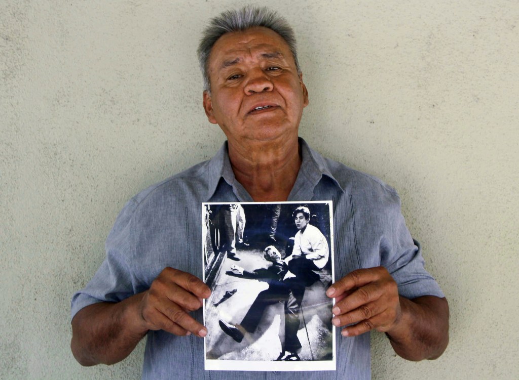 This photo provided by STORYCORPS shows Juan Romero holding a Los Angeles Times photograph that shows Romero with Sen. Robert F. Kennedy at the Ambassador hotel in Los Angeles moments after Kennedy was shot. The Los Angeles Times reported Thursday, Oct. 4, 2018, that Romero died Monday in Modesto, California, at age 68.  Romero was a busboy in June 1968 when Kennedy walked through the Ambassador Hotel kitchen after his victory in the California presidential primary and an assassin shot him in the head. He held the mortally wounded Kennedy as he lay on the ground, struggling to keep the senator's bleeding head from hitting the floor. 