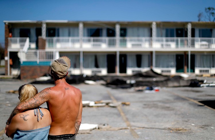 Residents line up for food from the Red Cross outside a damaged motel Tuesday in Panama City, Fla., where many residents continue to live in the aftermath of Hurricane Michael. Some residents rode out the storm and have no place to go even though many of the rooms at the motel are uninhabitable.
