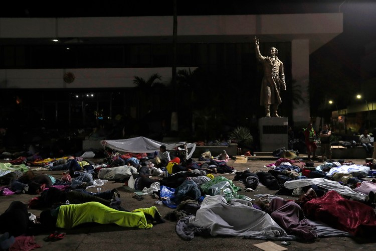 Honduran migrants hoping to reach the U.S. sleep in the southern Mexico city of Tapachula, Monday, Oct. 22, 2018, in a public plaza featuring a statue of Mexican national hero Miguel Hidalgo, a priest who launched Mexico's War of Independence in 1810. Keeping together for strength and safety in numbers, some huddled under a metal roof in the city's main plaza Sunday night. 