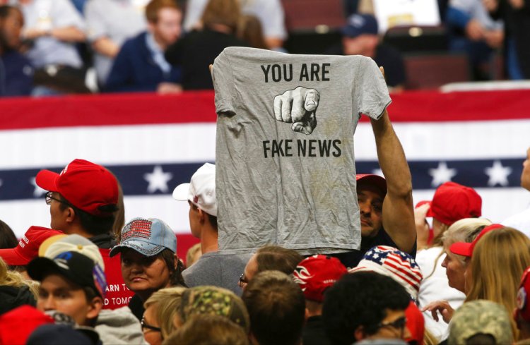 A Trump supporter holds up a T-shirt reading "You Are Fake News" before a rally by President Donald Trump in Rochester, Minn. on October 4. 