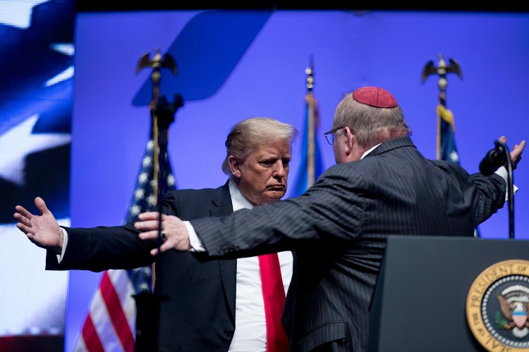President Trump and Rabbi Benjamin Sendrow hug after Sendrow prays at the 91st annual Future Farmers of America Convention and Expo at Bankers Life Fieldhouse in Indianapolis on Saturday, following a shooting in a Pittsburg synagogue. 