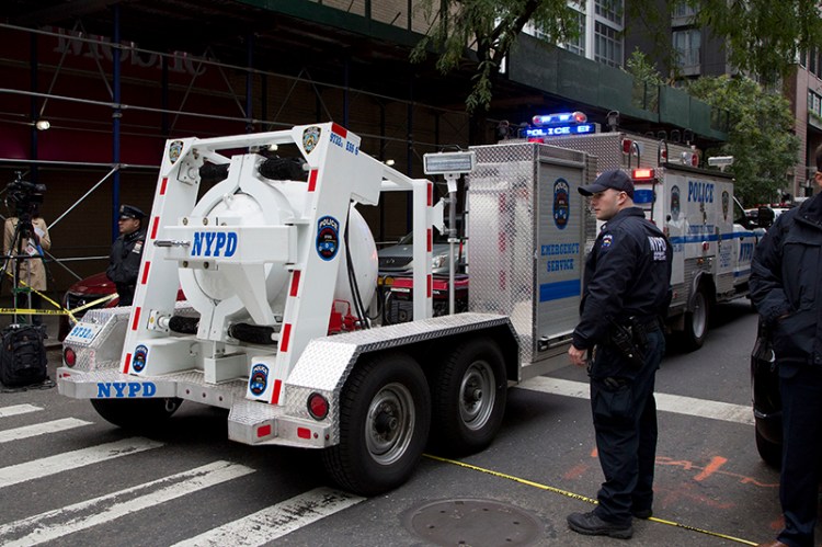 A police truck tows a total containment vessel to a post office in midtown Manhattan to dispose of a suspicious package on Friday.