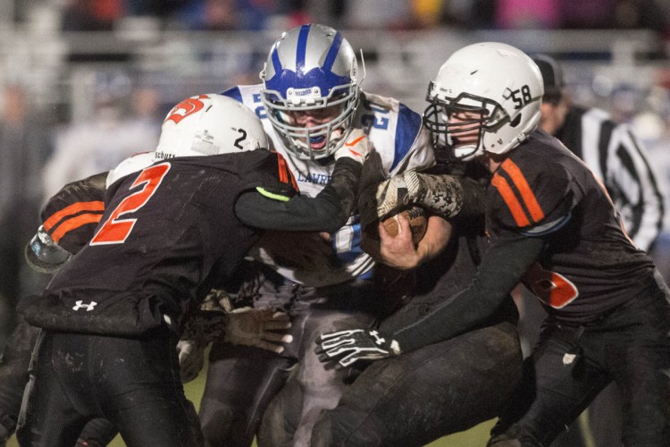 Lawrence's Kyle Carpenter, middle, gets tackled by Skowhegan defenders Spencer Wyman (2) and Chase Carey during a Pine Tree Conference Class B semifinal game Friday night in Skowhegan.