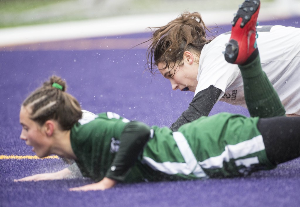 Fort Kent's Gabby Martin, left, gets knocked to the ground by Maranacook's Evelyn St. Germain in the Class C girls state championship game Saturday at Hampden Academy.