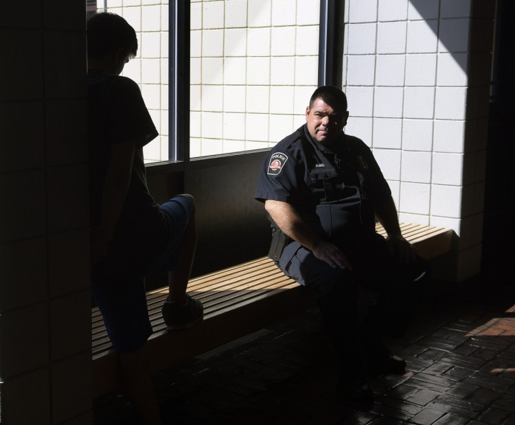School resource officer John Dalbec talks with a student in the lobby Oct. 10 at Oak Hill High School in Wales. Dalbec said the best part of his job is speaking with students.