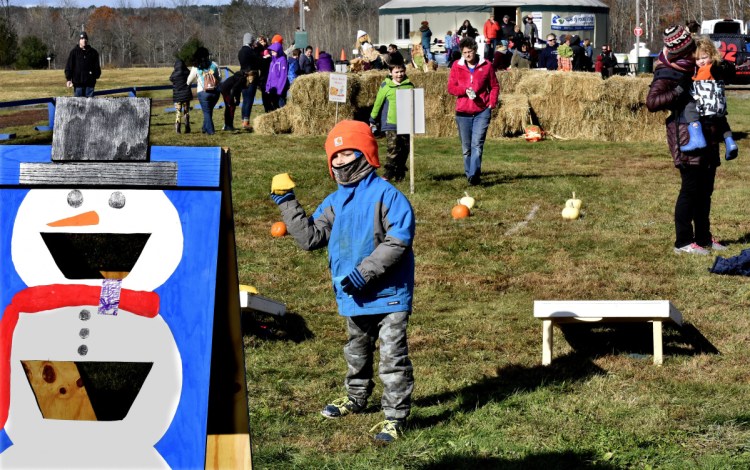 Joshua Dimartino takes aim with a bean bag at a snowman target during the Quarry Road Trails Fall Festival in Waterville on Sunday.