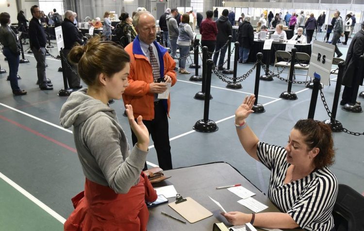 Colby College student Alexandria Fraize, left, swears the information she gave election clerk Allison Brochu is accurate before voting at Thomas College on Election Day as City Solicitor Bill Lee looks on.