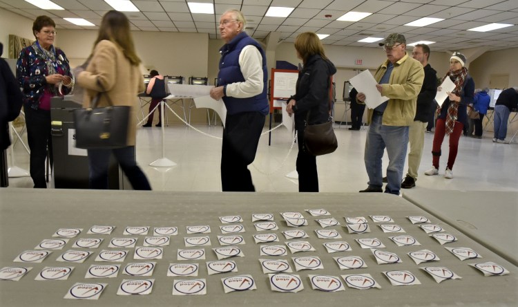 Winslow voters stand in line to cast ballots alongside a table full of voting stickers Tuesday at the Winslow VFW hall.