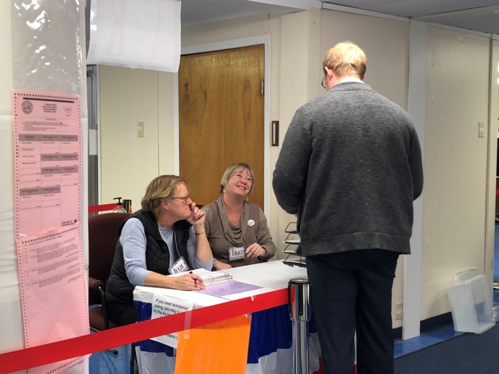 Deputy election clerks Julie Finley, left, and Traci Britten speak with a China voter on Tuesday night.