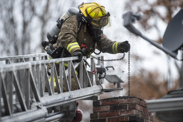 Oakland firefighter Randy Marshall extinguishes a chimney fire Friday at a residence on Mayland Street in Oakland. According to the Oakland Fire Department, residents should check their chimneys regularly, especially if wood is being burned.