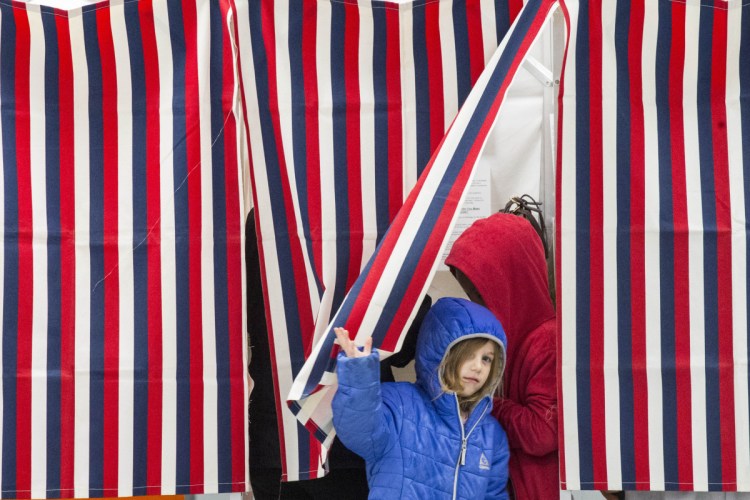 Alianna Shipley, 5, peers out from the voting booth that she is sharing with her brother Carter Hegarty, 8, and mother Jessica Lyon-Shipley at the Public Safety Building in Newport on Tuesday.