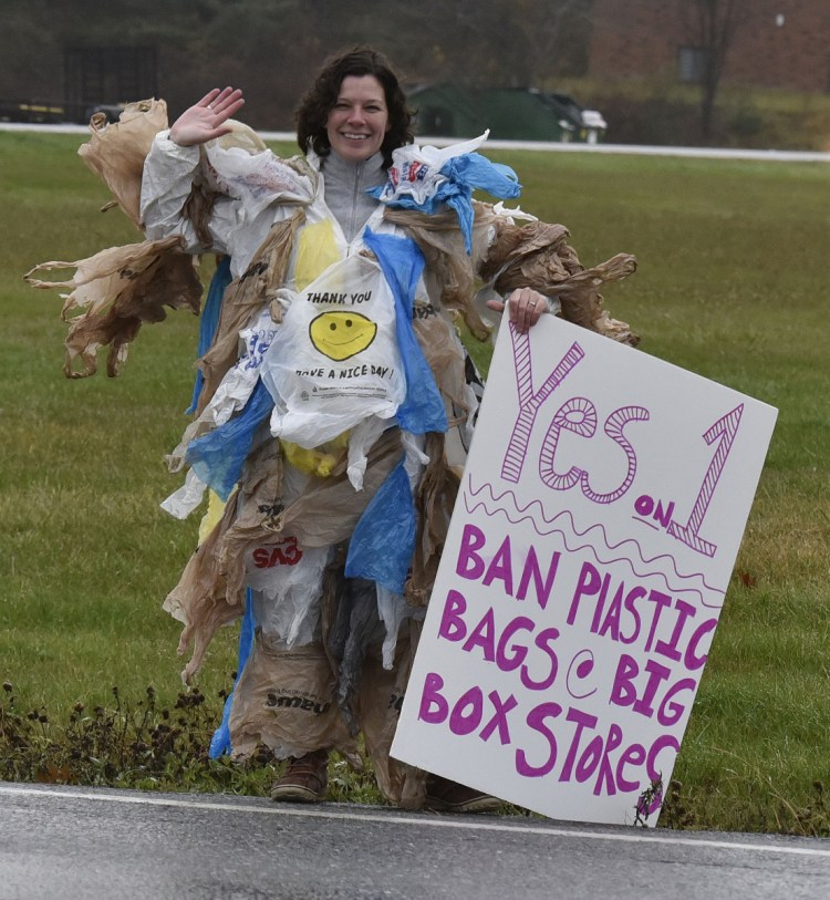 Draped in plastic bags, Yvette Meunier waves at voters and urges them to ban plastic bag use in local stores at the Thomas College polling station on Tuesday. Waterville residents voted to ban plastic bags in stores larger than 10,000 square feet.