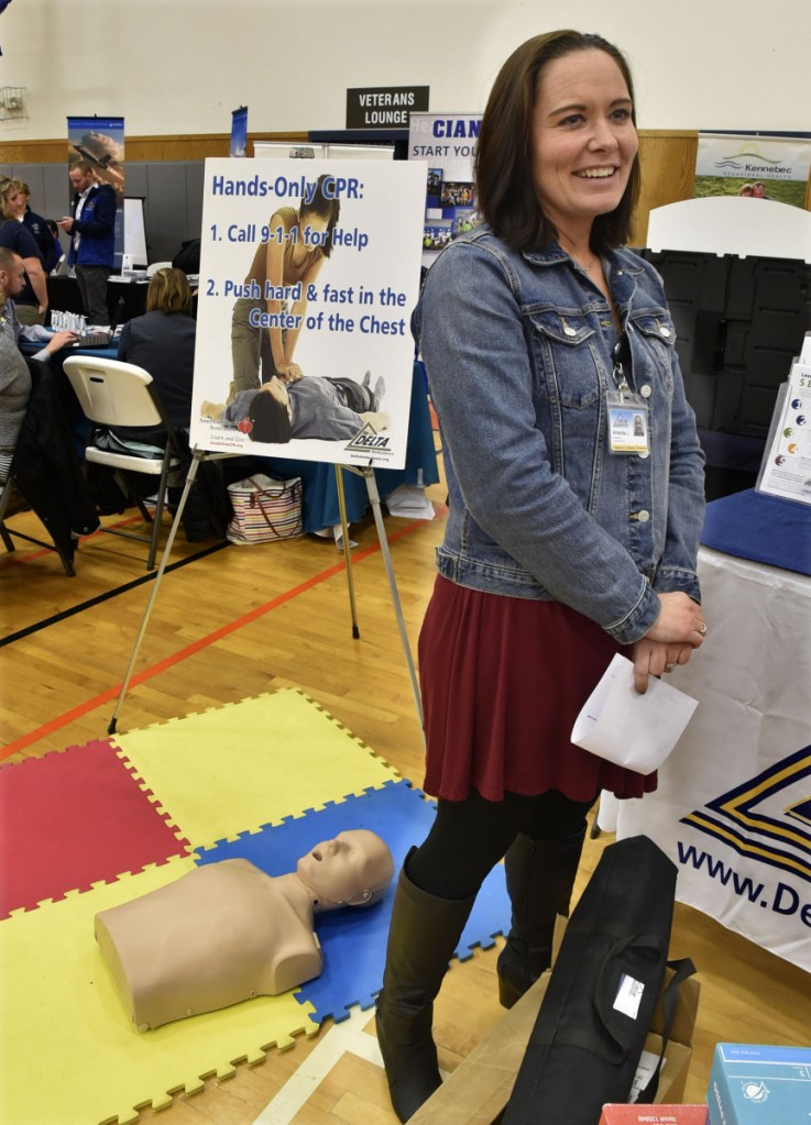 With a mannequin of a CPR patient as backdrop, Amanda Johnson, of Delta Ambulance, talks on Thursday about the need for more personnel during a job fair held at Kennebec Valley Community College's Hinckley campus.
