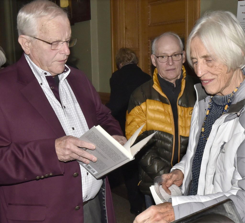 Earl Smith signs his book "Water Village, The Story of Waterville, Maine," for Louise Smith during a reception Thursday in the Waterville City Hall lobby. "I've read all of his books," Louise Smith said. Steve Collins is at center.