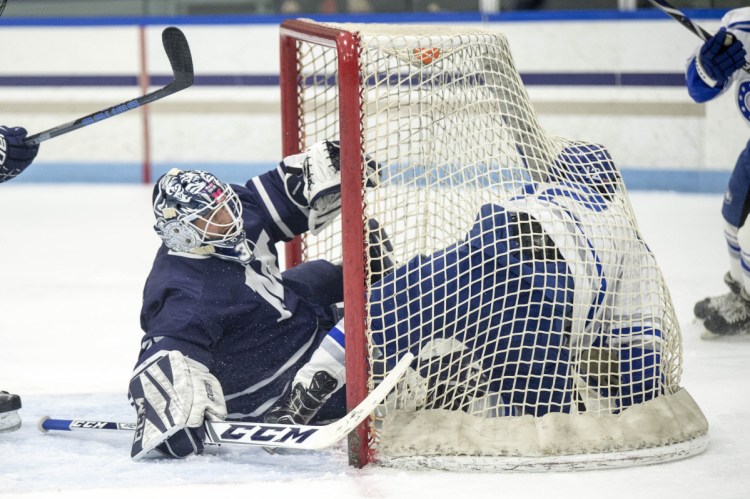 Colby College's Brendan Murphy (12) ends up in the goal on top of Middlebury College goalie Brian Ketchabaw (30) at Alfond Rink in Waterville on Friday.