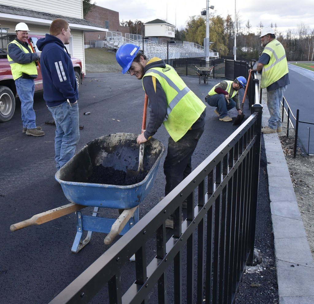 Workers with the E.L. Vining & Son Inc. company apply asphalt around the area leading to the $3.9 million athletic complex in Oakland on Nov. 8. The project includes a new playing field, bleachers and track.